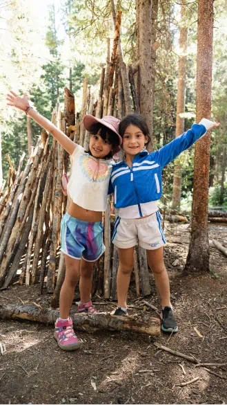 Two girls smile at the camera with their arms out at Camp Aspen Snowmass