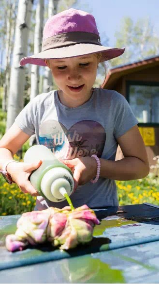 Little girl uses a squirt bottle to dye  t-shirt during a tie dye  activity at Camp Aspen Snowmass