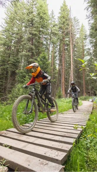 two kids ride along a wood trail at Snowmass, during a bike activity at camp aspen snowmass