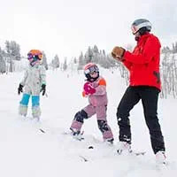 Ski instructor applauding kids learning to ski