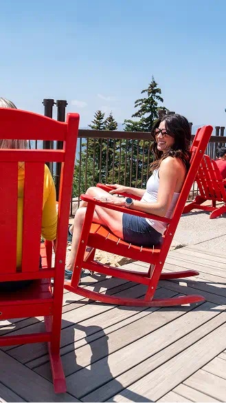 Two woman sit in red lawn chairs atop aspen mountain